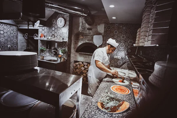 Chef-kok maakt pizza in de keuken van het restaurant — Stockfoto