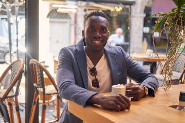 Adam kafede kahvenin tadını çıkarıyor.