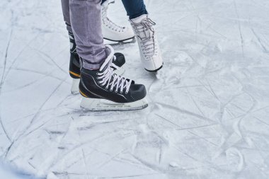 Young loving couple skating at ice rink outdoors
