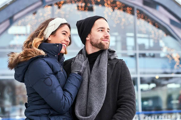 Casal feliz namoro na pista de gelo, abraçando e aproveitando o tempo de inverno — Fotografia de Stock