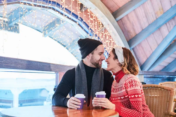 Pareja joven en una cita en el café, hablando y besándose en Navidad — Foto de Stock