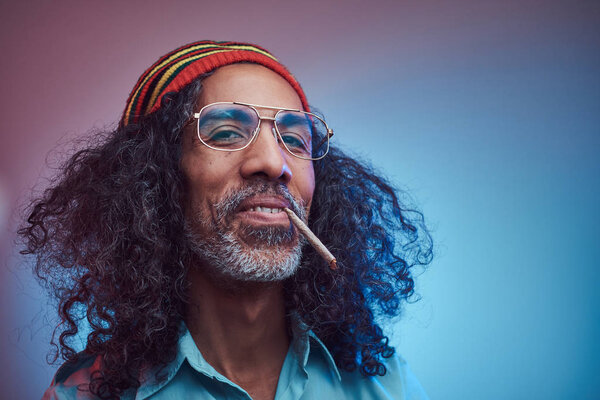 Studio portrait of African Rastafarian male smoking cigarettes