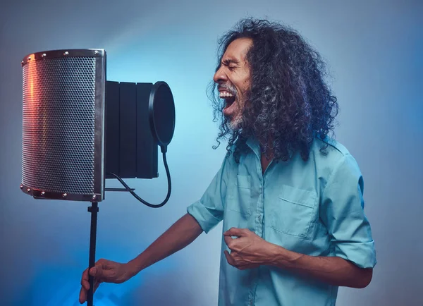 Afrikanischer Gesangskünstler im blauen Hemd, der im Tonstudio emotional Songs schreibt. — Stockfoto