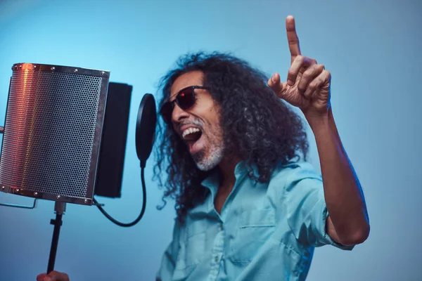 Artista vocal africano vestindo uma camisa azul escrevendo emocionalmente música no estúdio de gravação . — Fotografia de Stock