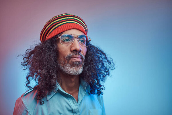 Studio portrait of African Rastafarian male wearing a blue shirt and beanie.