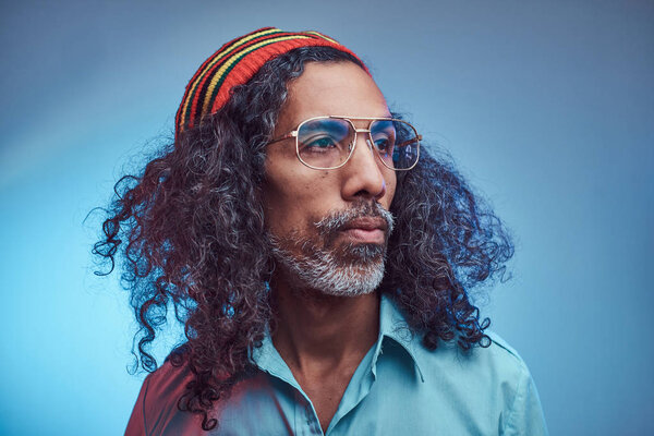 Studio portrait of African Rastafarian male wearing a blue shirt and beanie.