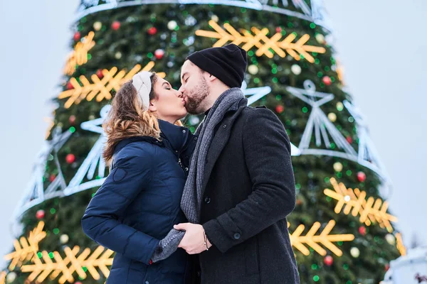 Coppia felice indossa vestiti caldi in piedi vicino a un albero di Natale della città, godendo di trascorrere del tempo insieme — Foto Stock