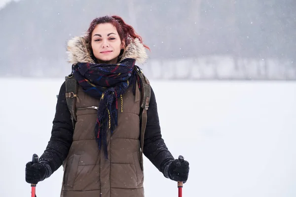 Menina ruiva bonita fazendo trekking ao lado de uma floresta nevada — Fotografia de Stock