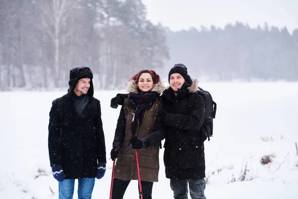 Des amis marchent dans la forêt enneigée froide se tiennent dans un câlin et regardent la caméra . — Photo