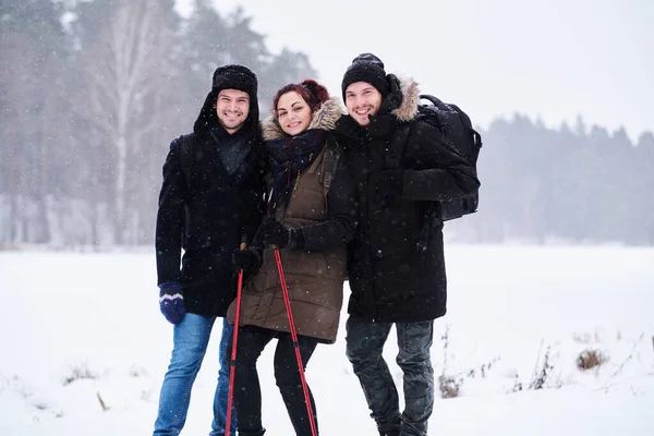 Amigos caminham no frio floresta nevada ficar em um abraço e olhar para a câmera . — Fotografia de Stock