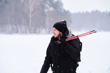 Karlı bir ormanın yanında yürüyüş yapan mutlu adam.