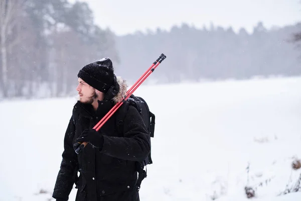 Happy guy doing trekking next to a snowy forest — Stock fotografie