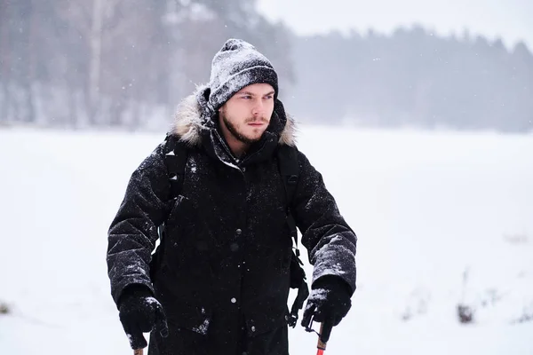 Happy guy doing trekking next to a snowy forest — Stock fotografie