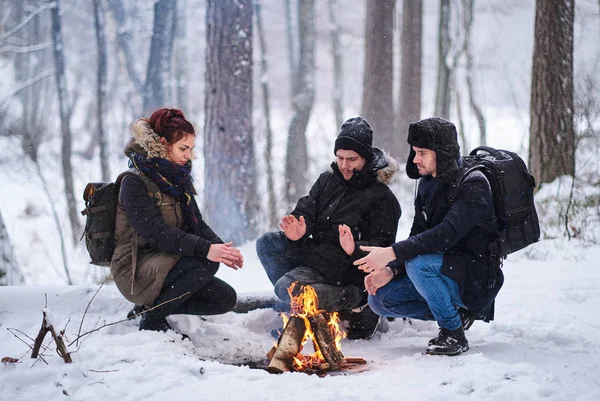 Friends of travelers bask in a fire in the snowy forest — Stock Photo, Image
