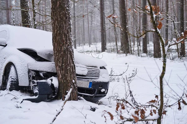 Carro quebrado cai na árvore depois de perder o controle na estrada escorregadia na floresta nevada . — Fotografia de Stock