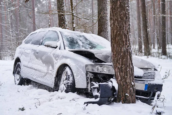 Carro quebrado cai na árvore depois de perder o controle na estrada escorregadia na floresta nevada . — Fotografia de Stock