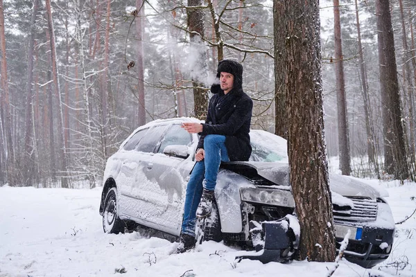 The driver smokes a cigarette next to the wrecked car. — Stock Photo, Image