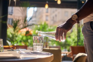 Adam bardağa su döküyor.