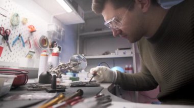 Elektronik tamircisi akıllı telefon panosunda lehimleme işi yapıyor.