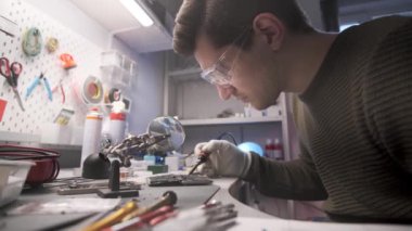 Elektronik tamircisi akıllı telefon panosunda lehimleme işi yapıyor.