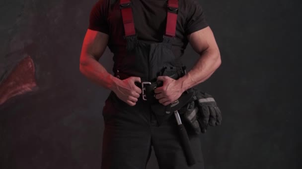 Odważny człowiek w mundurze strażaka stojący pod szarą ścianą i odwracający wzrok. — Wideo stockowe