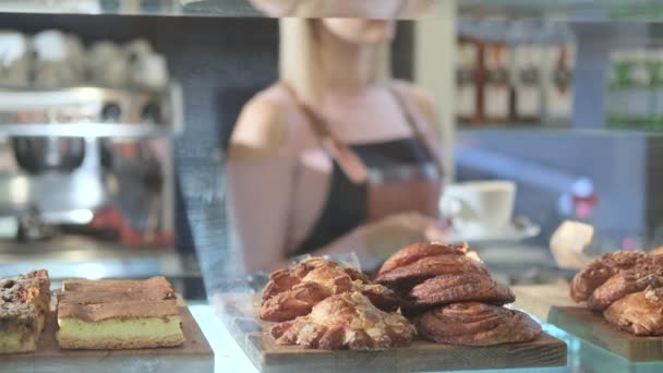 Fresh pastries in the confectionery store. Close-up products with saleswoman on a background — ストック動画