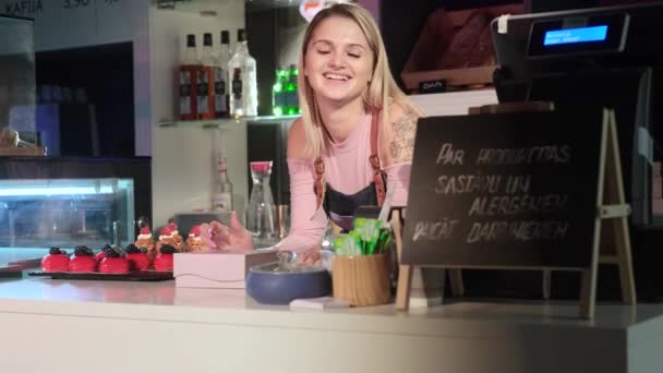 Adorable girl seller laughs leaning on the counter in the pastry shop — ストック動画