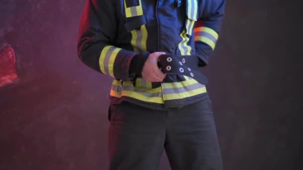 Γενναίος πυροσβέστης φοράει στολή ενώ στέκεται σε ένα γκρίζο τοίχο — Αρχείο Βίντεο