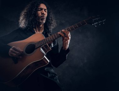 Akustik gitarlı çekici orta yaşlı bir adamın portresi.