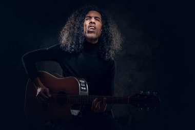 Adam fotoğrafçıya poz verirken gitar çalıyor.