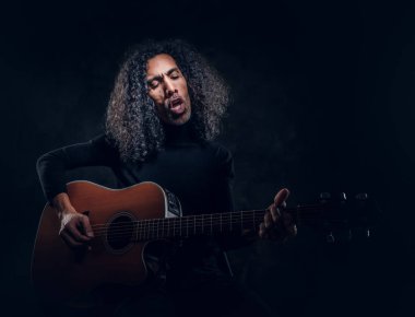 Adam fotoğrafçıya poz verirken gitar çalıyor.