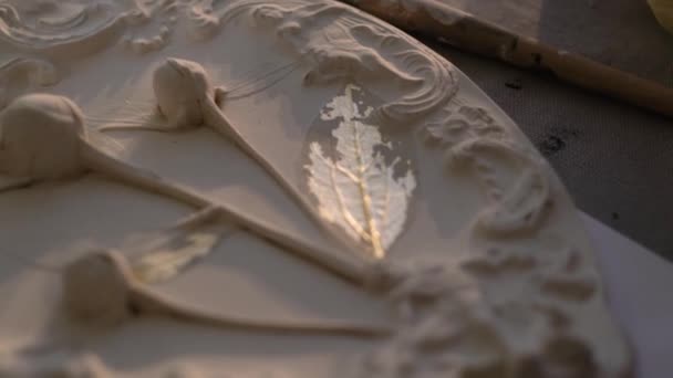 Artiste travaille sur plaque décorative blanche 