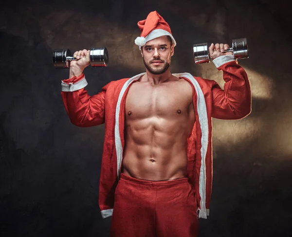 Schöner Kerl im Weihnachtsmann-Kostüm mit Hanteln — Stockfoto