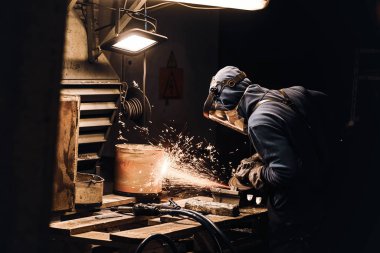 Çalışkan adam atölyede metalle çalışıyor.
