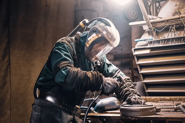 Staranny człowiek pracuje z metalem w warsztacie — Zdjęcie stockowe