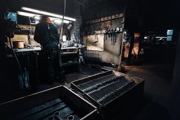 Pečlivý muž pracuje s kovem v dílně — Stock fotografie