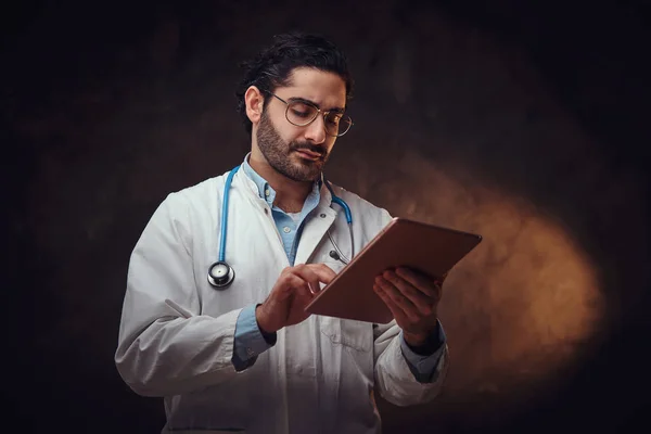 Portret van een gefocuste arts met tablet in handen — Stockfoto