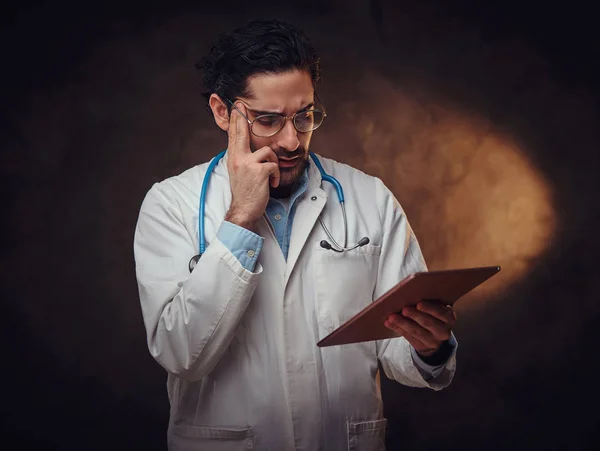 Portret van een gefocuste arts met tablet in handen — Stockfoto