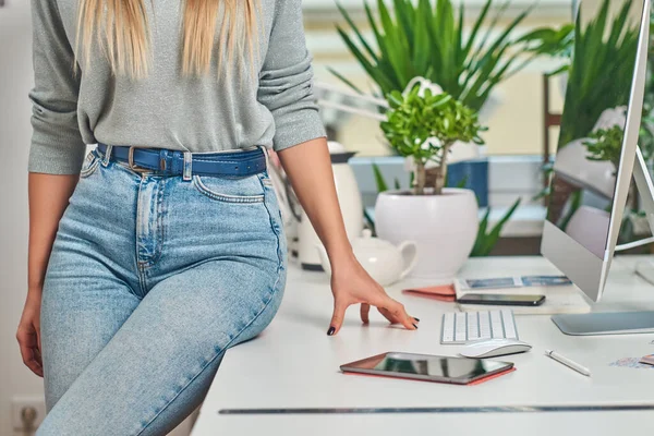 Vrouw in jeans zit op tafel — Stockfoto