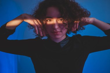 Yüzünde ışık çizgisi olan kıvırcık kadın.