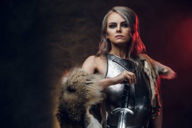 Kılıç tutan güzel savaşçı bir kadının portresi çelik kol ve kürk giyiyor. Fantezi modası. Ciri rolünde Cosplayer Cadıdan.