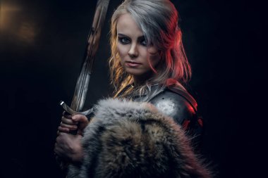 Kılıç tutan güzel savaşçı bir kadının portresi çelik kol ve kürk giyiyor. Fantezi modası. Ciri rolünde Cosplayer Cadıdan.