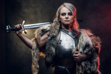 Kılıç tutan güzel savaşçı bir kadının portresi çelik kol ve kürk giyiyor. Fantezi modası. Ciri rolünde Cosplayer Cadıdan.