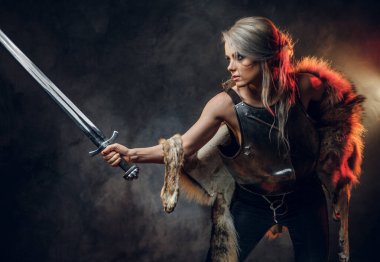 Kılıç tutan güzel savaşçı bir kadının portresi çelik kol ve kürk giyiyor. Fantezi modası. Ciri rolünde Cosplayer Cadıdan.