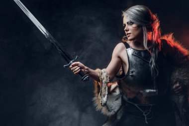 Kılıç tutan güzel savaşçı bir kadının portresi çelik kol ve kürk giyiyor. Fantezi modası. Ciri rolünde Cosplayer Cadıdan.