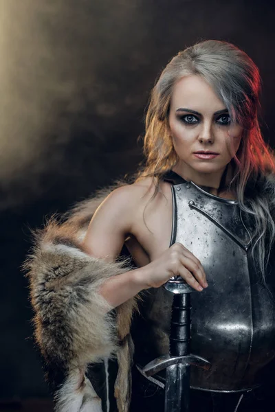 Portret pięknej wojowniczki trzymającej miecz w stalowej sukni i futrze. Fantazyjna moda. Cosplayer jako Ciri z Wiedźm. — Zdjęcie stockowe