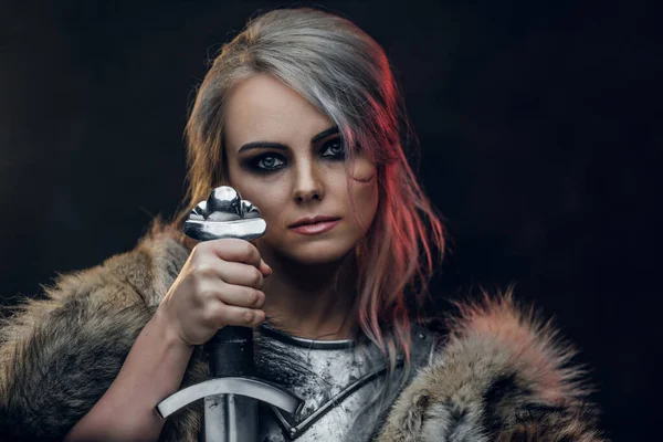 Retrato de una hermosa guerrera sosteniendo una espada con coraza de acero y piel. Moda de fantasía. Cosplayer como Ciri de The Witcher . —  Fotos de Stock
