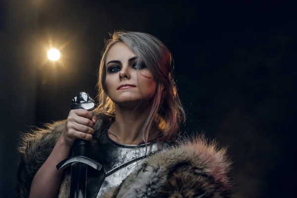 Portret pięknej wojowniczki trzymającej miecz w stalowej sukni i futrze. Fantazyjna moda. Cosplayer jako Ciri z Wiedźm. — Zdjęcie stockowe