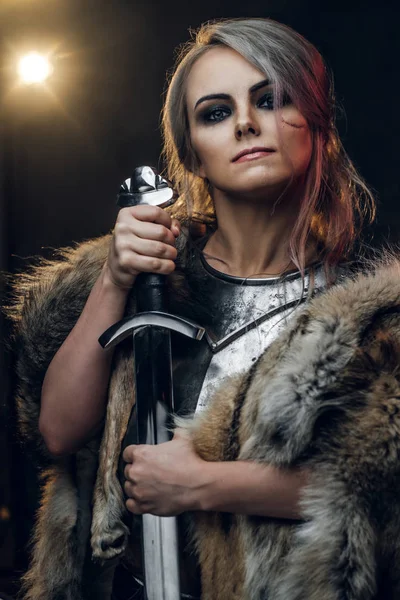 Ritratto di una bellissima guerriera con una spada che indossa corazza d'acciaio e pelliccia. Moda fantasy. Cosplayer come Ciri de La Strega . — Foto Stock