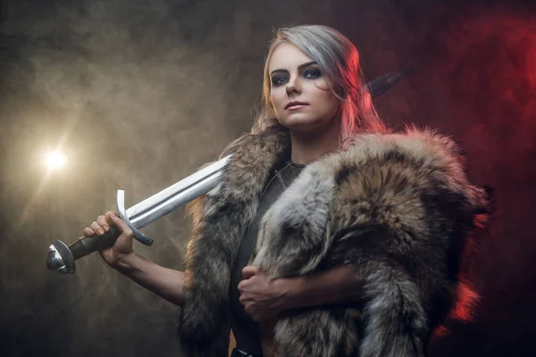 Ritratto di una bellissima guerriera con una spada che indossa corazza d'acciaio e pelliccia. Moda fantasy. Cosplayer come Ciri de La Strega . — Foto Stock